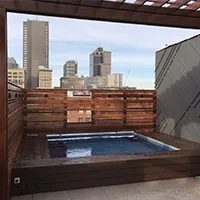 Rooftop Endless Pool with cedar privacy screen and city skyline — Jackson Builders project photo 1