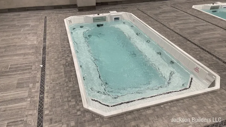Close view of a single HydroWorx therapy pool at Jacksonville State University with jets running, showing the digital control panel, tiled coping and the Gamecocks logo on the pool wall.